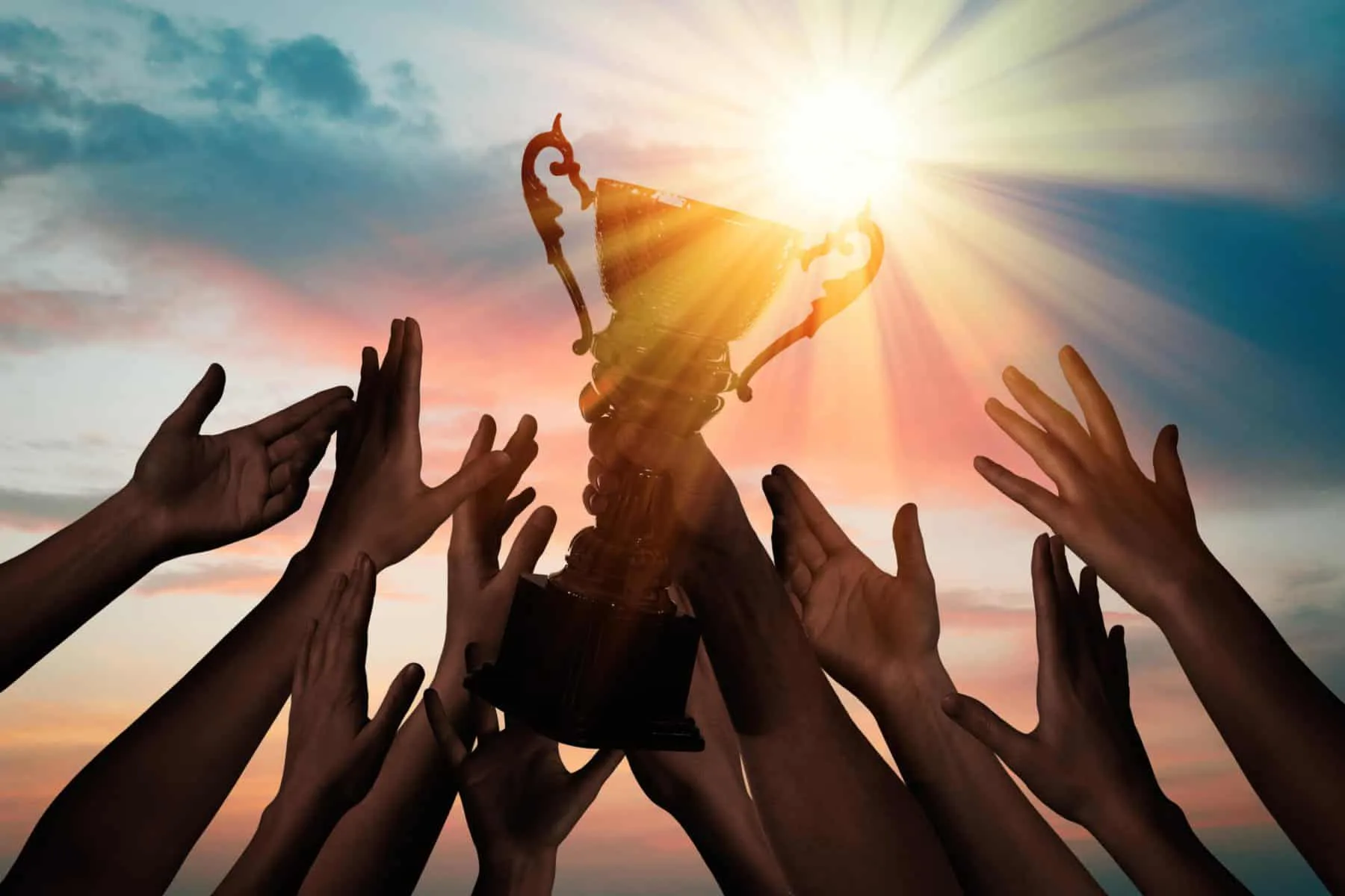 Winning team with gold trophy cup against shining sun in sky | DBIA Announces 2026 National Design-Build Project/Team Award Winners